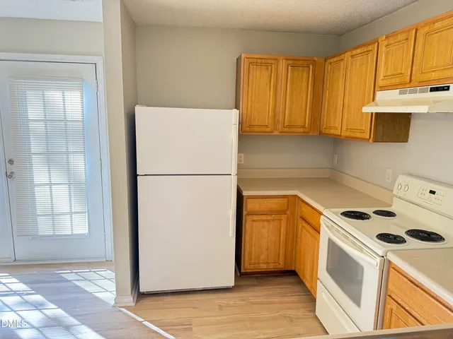 a kitchen with a refrigerator a stove top oven and cabinets
