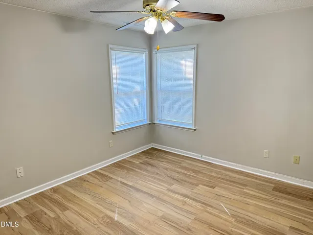 an empty room with a chandelier fan and windows