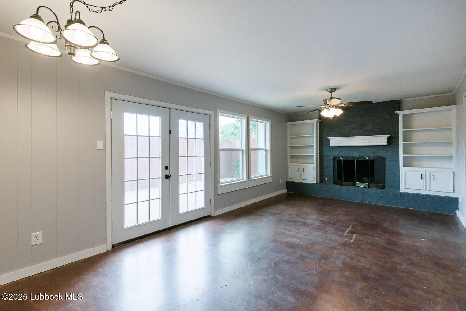 4314 52nd Street, Unit A Lubbock, TX 79413 - Photo 32 of 54 an empty room with windows fireplace and a chandelier