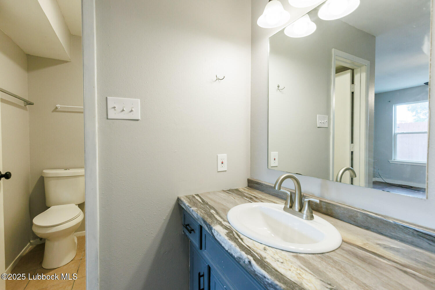 4314 52nd Street, Unit A Lubbock, TX 79413 - Photo 50 of 54 a bathroom with a granite countertop sink a toilet and a mirror