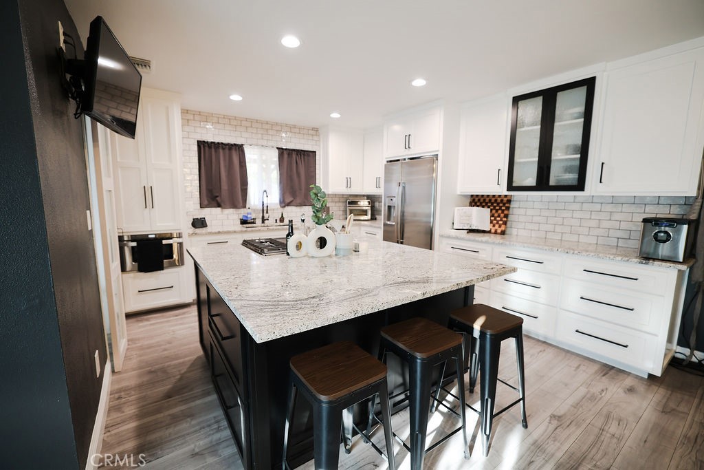 1156 3rd Street Calimesa, CA 92320 - Photo 14 of 34 a large kitchen with kitchen island a dining table chairs stainless steel appliances and cabinets