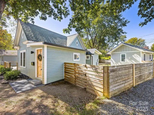 a view of a wooden house with a large window and large tree