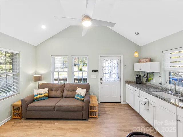 a large living room with stainless steel appliances granite countertop couches a large window with wooden floor