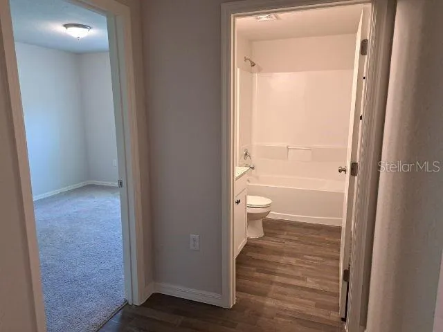 a bathroom with a granite countertop bathtub shower sink vanity and toilet
