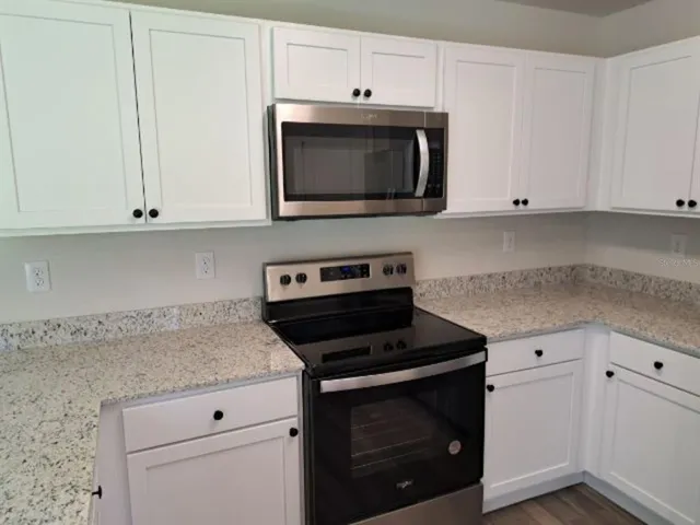 a kitchen with granite countertop white cabinets and stainless steel appliances