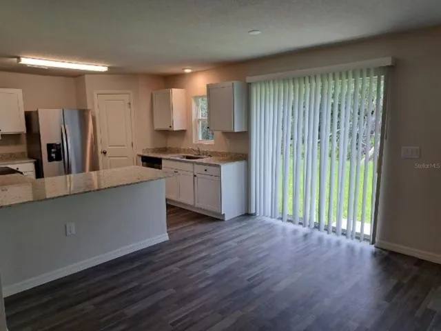 a large kitchen with stainless steel appliances granite countertop a stove a sink and a large window