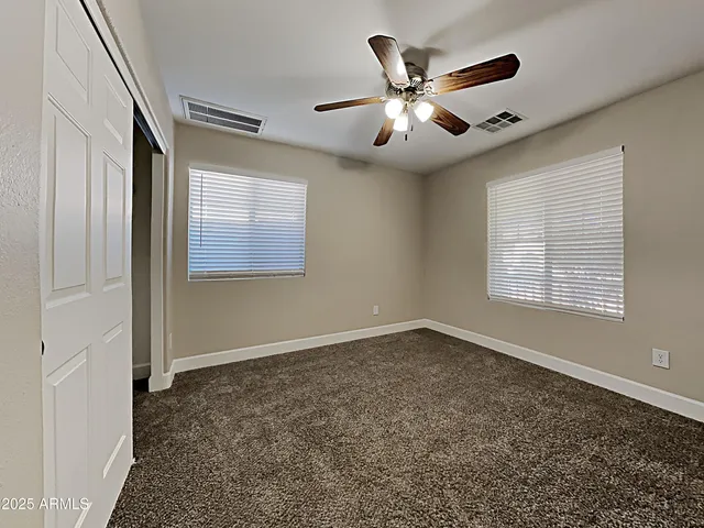 an empty room with windows and fan
