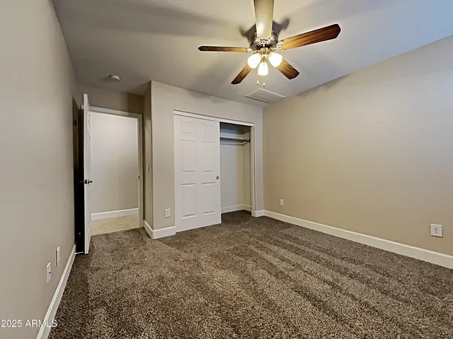 an empty room with closet and a chandelier fan