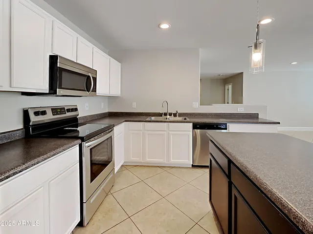 a white kitchen with stainless steel appliances granite countertop a sink and a stove