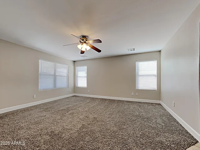 an empty room with windows and chandelier fan