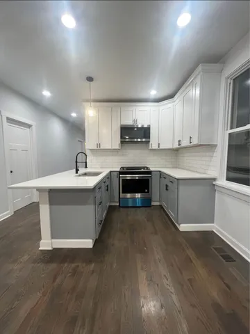 a large kitchen with stainless steel appliances kitchen island a sink dishwasher a stove and a refrigerator with wooden floor