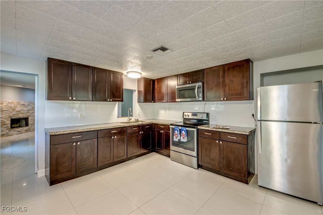 19330 Meredith Road North Fort Myers, FL 33917 - Photo 14 of 50 a kitchen with stainless steel appliances granite countertop a refrigerator stove a sink dishwasher and microwave