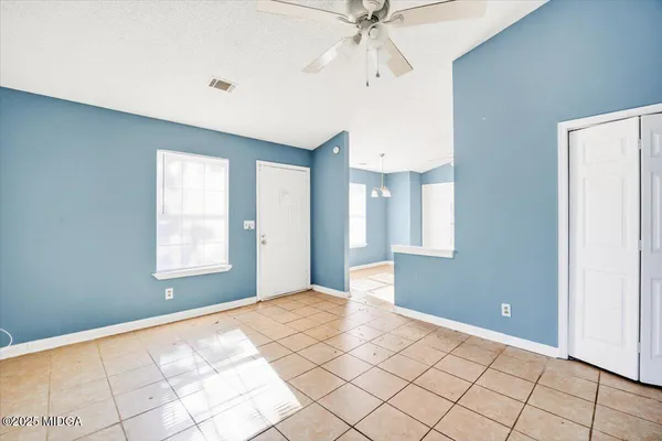 a view of an empty room with window and chandelier fan
