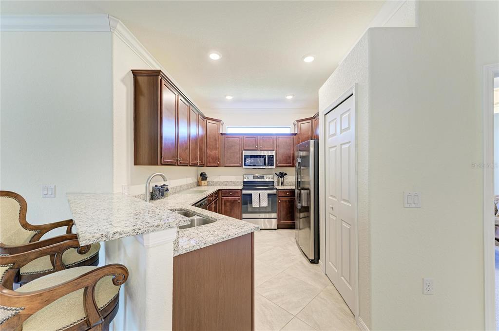 12440 Amica Loop Venice, FL 34293 - Photo 25 of 87 a kitchen with stainless steel appliances granite countertop a refrigerator and a stove top oven