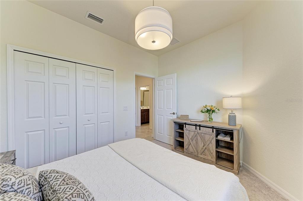 12440 Amica Loop Venice, FL 34293 - Photo 47 of 87 a bedroom with a bed and a chandelier