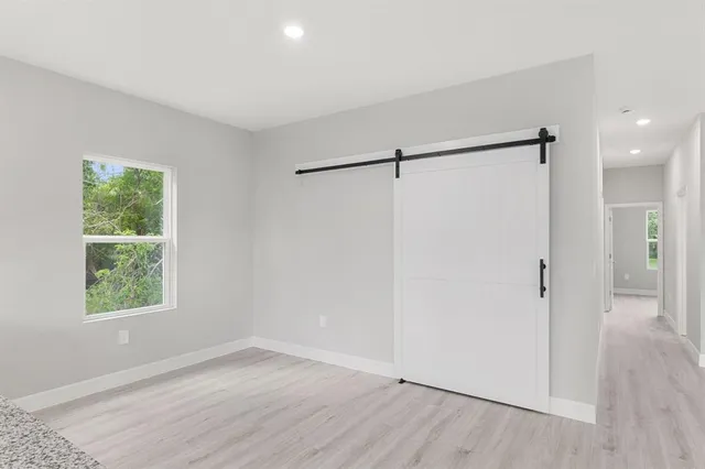 an empty room with wooden floor closet and windows