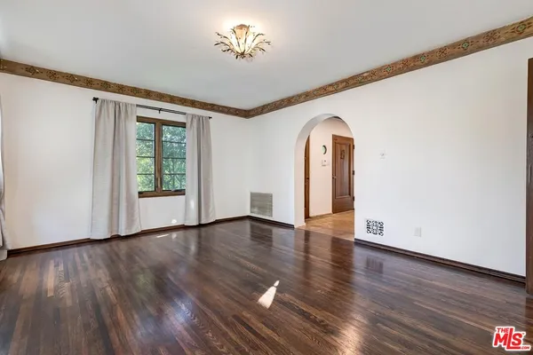 a view of an empty room with a window and wooden floor