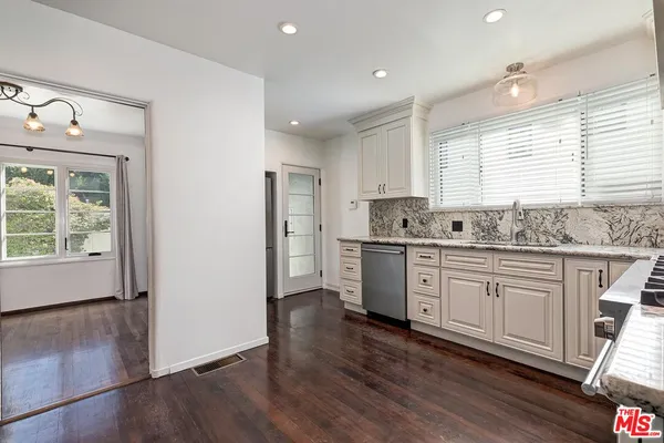 a kitchen with granite countertop a sink cabinets stainless steel appliances and window