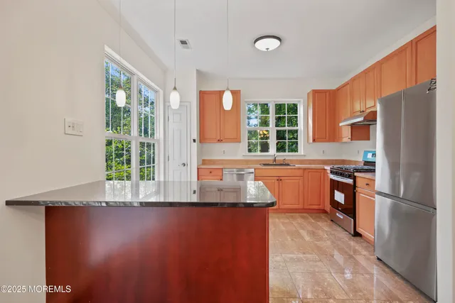 a kitchen with granite countertop a refrigerator stove top oven and sink