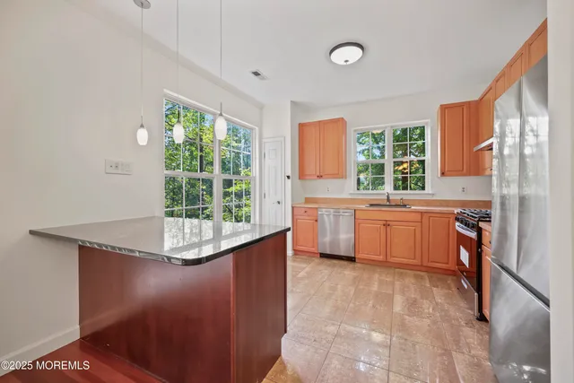 a kitchen with stainless steel appliances granite countertop a refrigerator a stove a sink and dishwasher with wooden floor