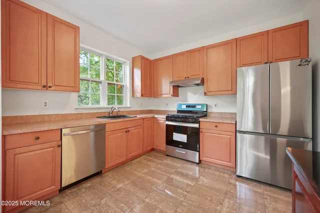 a view of an empty room with wooden floor fireplace and a window