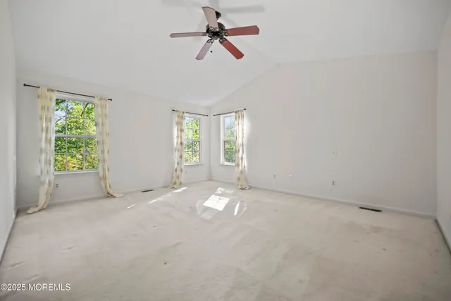 an empty room with chandelier fan and windows