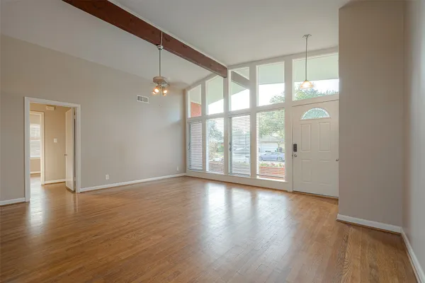 a view of an empty room with wooden floor and a window