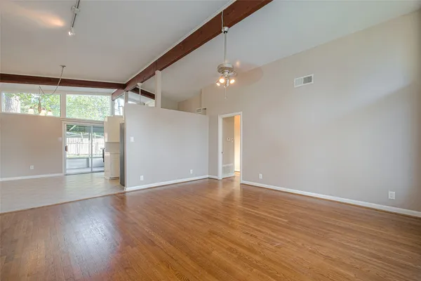a view of an empty room with wooden floor and a window