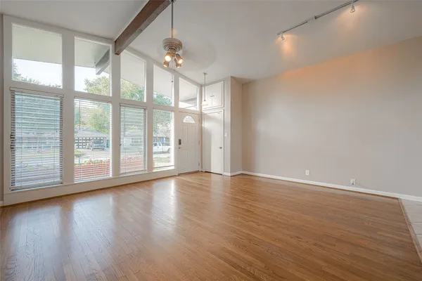 a view of an empty room with wooden floor and a window