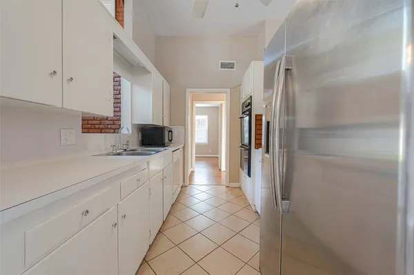 a large white kitchen with a sink and refrigerator