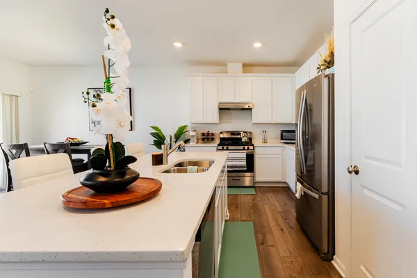 a kitchen with kitchen island a counter top space a sink stainless steel appliances and cabinets