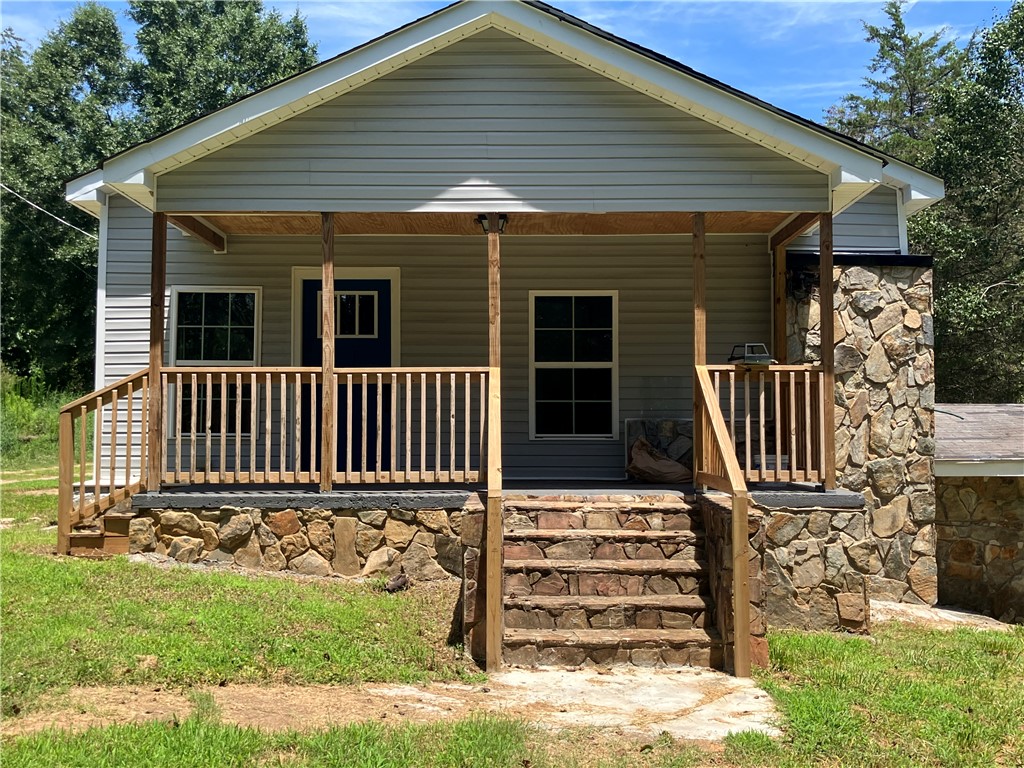 1305 A Lebanon Road Pendleton, SC 29670 - Photo 1 of 5 A welcoming front porch with natural wood railings beckons, complemented by a stately stone foundation and chimney.