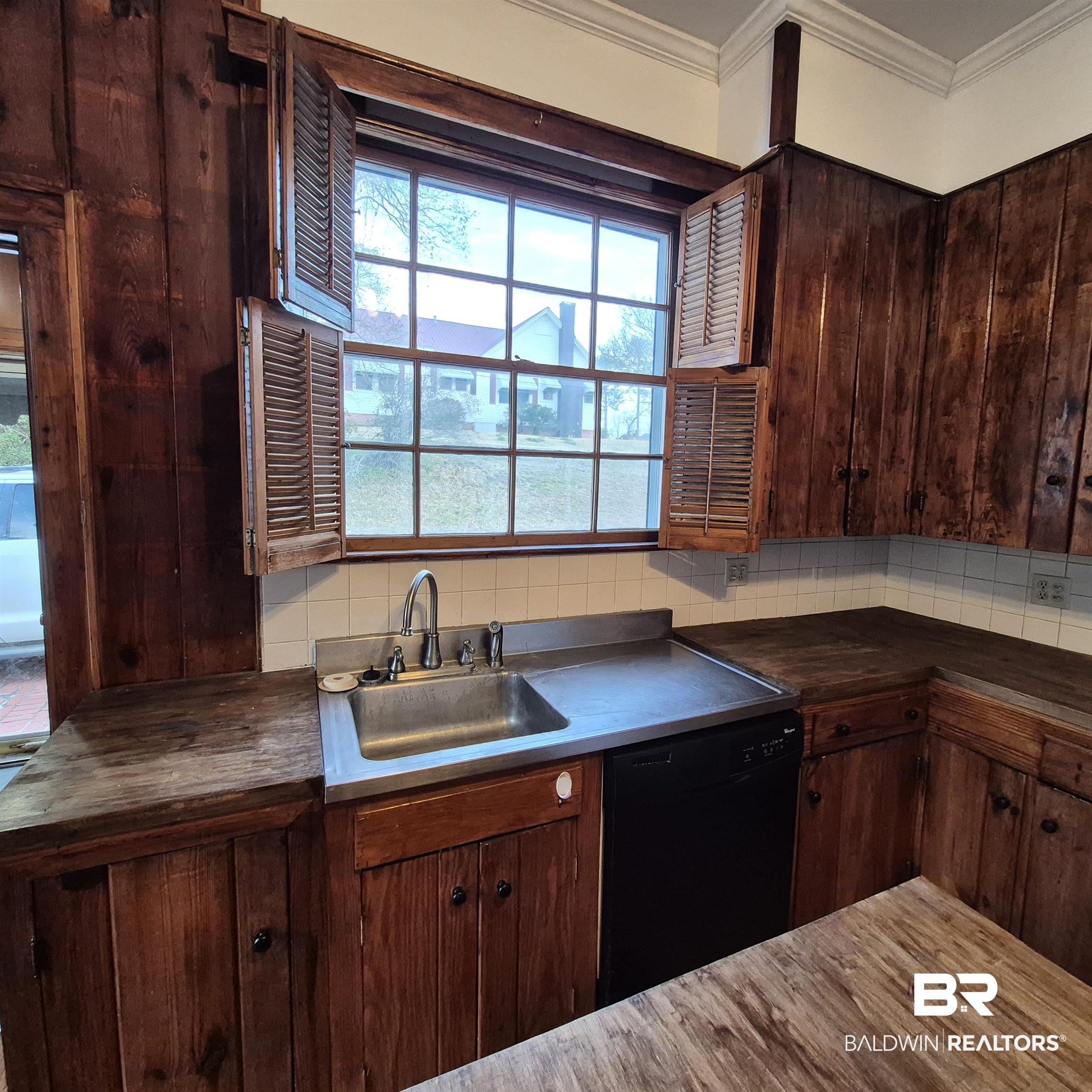 308 Rural Street Evergreen, AL 36401 - Photo 18 of 40 Kitchen featuring black dishwasher, decorative backsplash, dark wood finish cabinets, and ornamental molding