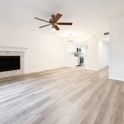 a view of a livingroom with a ceiling fan wooden floor and a ceiling fan