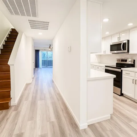 a view of kitchen with microwave a stove top oven and wooden floor