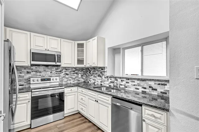 a kitchen with granite countertop white cabinets stainless steel appliances and sink