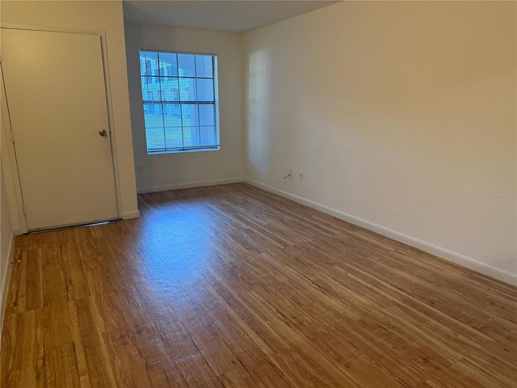 2323 McCoy Road, Unit 701 Orlando, FL 32809 - Photo 7 of 11 an empty room with wooden floor and windows