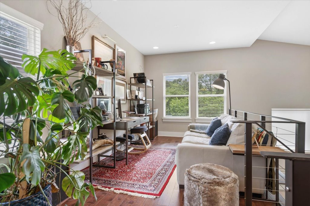 1800 Webberville Road, Unit B Austin, TX 78721 - Photo 21 of 30 Open loft space featuring wood-finish flooring, two window openings with horizontal blinds, recessed ceiling lighting, and a partial metal railing