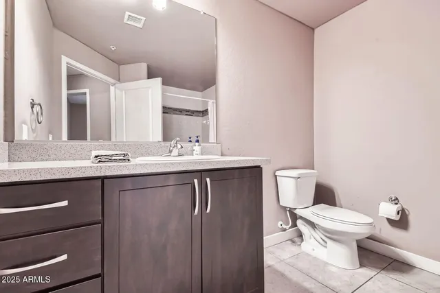 a bathroom with a granite countertop toilet sink and mirror