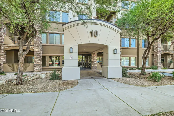 a view of a white house with large windows and a small yard