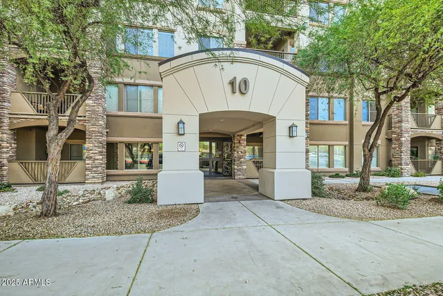 a view of a white house with large windows and a small yard