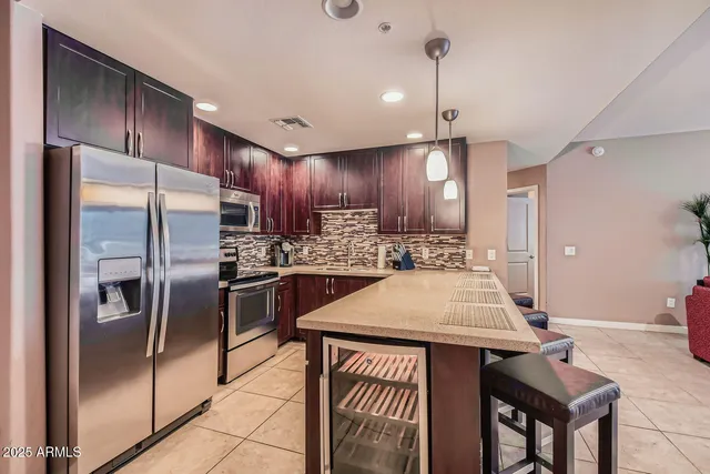 a kitchen with stainless steel appliances kitchen island granite countertop a refrigerator a sink a stove and island