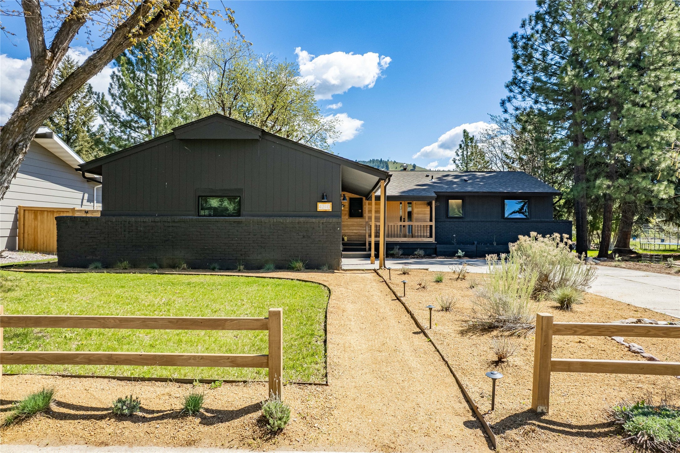 4210 Lincoln Road Missoula, MT 59802 - Photo 1 of 1 View of front of home featuring a porch, brick siding, fence, and driveway