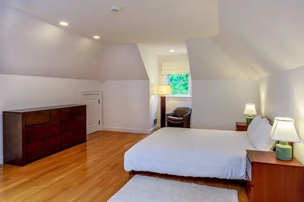 a spacious bedroom with a bed and a dresser with wooden floor