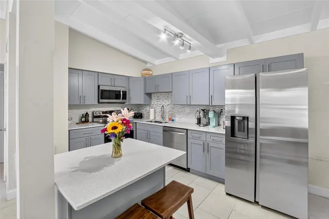 a kitchen with a refrigerator a stove a sink and white cabinets
