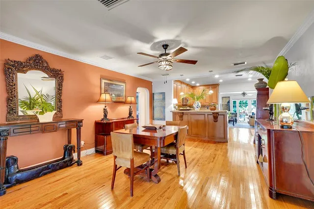 a dining room with chandelier fan and wooden floor