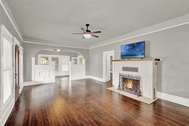 a view of an empty room with wooden floor fireplace and a window