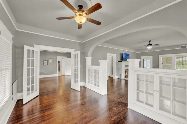 a view of an empty room with wooden floor and a ceiling fan