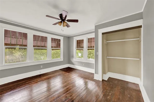 a view of an empty room with a window and wooden floor