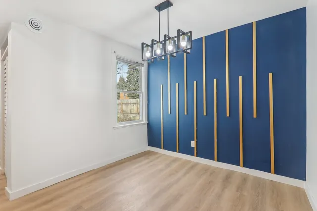 a view of an empty room with chandelier and wooden floor